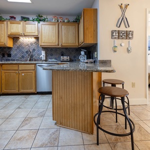 Gather around the kitchen bar for meals, surrounded by charming decor and warm wood cabinetry