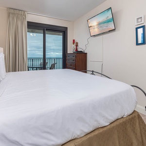 Unwind in this comfortable master bedroom featuring a plush king bed, decorative accents, and a beach view