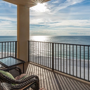 Relax on the balcony with comfortable seating, enjoying the sparkling water and serene beach view just below