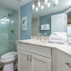 The master bathroom features elegant marble countertops, a glass shower, and plush towels for a refreshing retreat