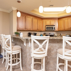 This kitchen features warm wood cabinetry, granite countertops, and a cozy breakfast bar, perfect for morning coffee