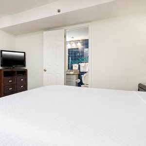 This cozy bedroom features a large king bed, a flat-screen TV, and an inviting bathroom with colorful tile accents