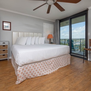Master suite bedroom featuring a king bed, a cozy chair, and access to a balcony with scenic views