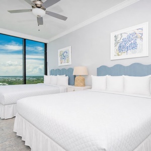 Soothing guest bedroom with two queen beds, stylish decor, and expansive windows showcasing beautiful views