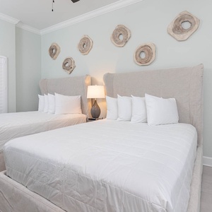Drift off on plush queen beds beneath a warm lamp and fluff pillows for a restful retreat in this guest room