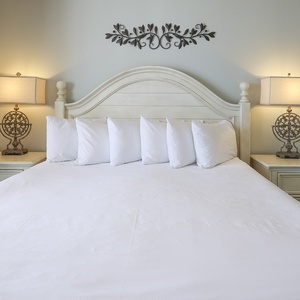 Cozy master bedroom featuring a large king bed with plush bedding, elegant lamps, and soft blue walls for a serene atmosphere