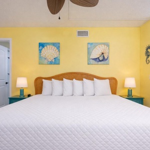 Relax on the plush king bed in this guest suite with vibrant colors and coastal art