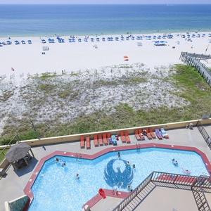 The vibrant pool area with guests enjoying the water, surrounded by lounge chairs and a view of the beach