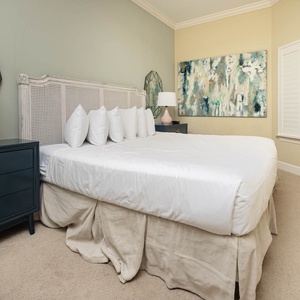 This bedroom features a plush king bed with white linens, stylish decor, and a vibrant artwork, creating a serene retreat