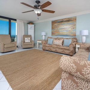 Living area featuring a patterned sofa with queen sleeper, two armchairs, offering stunning views of the beach