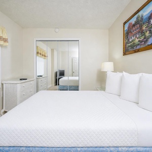 This cozy bedroom features a comfortable bed, a TV for entertainment, and a charming view of the mirrored wardrobe