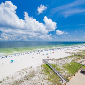 Expansive view of a pristine beach with colorful umbrellas, framed by vibrant blue skies and gentle waves lapping the shore