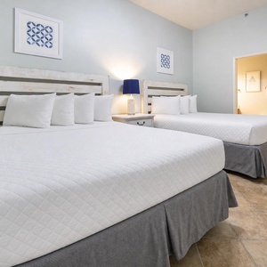 Rest in the comfortable guest room featuring two queen beds, soft linens, and charming coastal decor