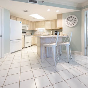 The kitchen area featuring white cabinetry, a breakfast bar with seating, and a view into the adjacent master bedroom