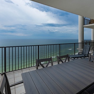This spacious balcony features a large dining table and comfortable seating, perfect for enjoying beachfront views
