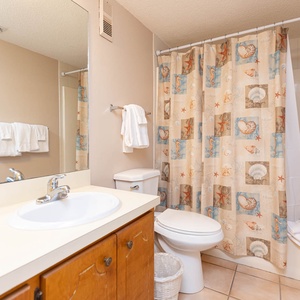 The bathroom features a clean design with a spacious vanity, decorative shower curtain, and fresh towels