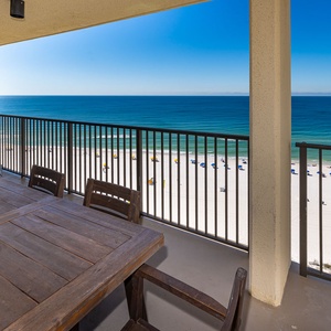 A table with six chairs overlooks the beach front, providing a perfect spot to enjoy the coastal view