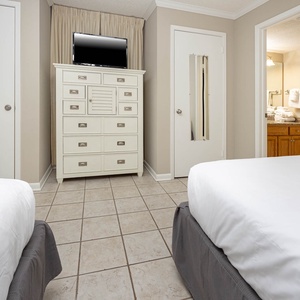 Relax in this cozy guest bedroom featuring two comfortable queen beds, a dresser, and adjoining bathroom