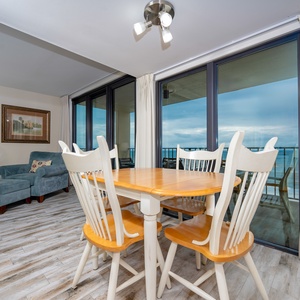 Cozy living area with a cozy blue chair, dining table, and panoramic views through floor-to-ceiling windows