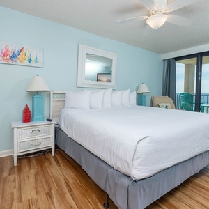 The bright master suite features a cozy king bed, vibrant decor, and a balcony with a beautiful view of the water