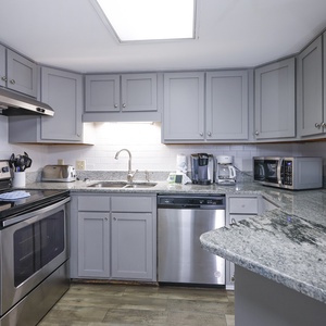 The kitchen features gray cabinetry, granite countertops, Keurig and coffee maker, creating a functional cooking space