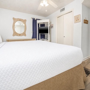 Inviting bedroom featuring a plush king bed, a wall-mounted TV, and a decorative mirror, perfect for relaxation