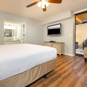 A cozy master bedroom features a king bed, wall-mounted TV, and access to a private ground floor outdoor patio
