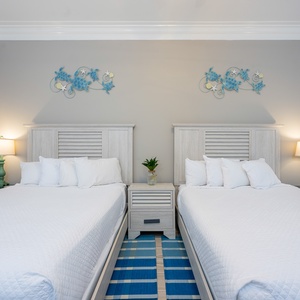 Dual queen guest room with playful sea turtle wall accents and soft linens