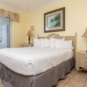 The master bedroom features a plush bed, elegant decor, and a private balcony with a stunning beachfront view