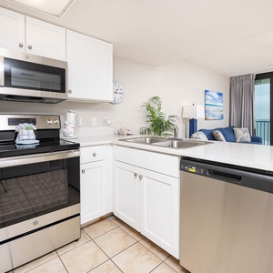 Cook meals in the bright kitchen featuring stainless steel appliances, a spacious bar, and views of the living area