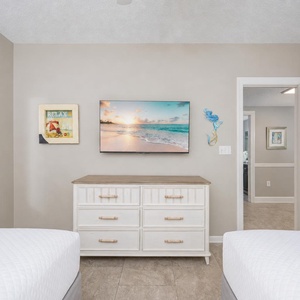 Double beds in the guest suite frame your view of the TV and charming coastal wall art for quiet evenings