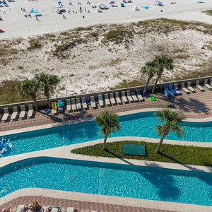 Relax by the lazy river surrounded by palm trees, with a view of the pristine beach and colorful sun loungers