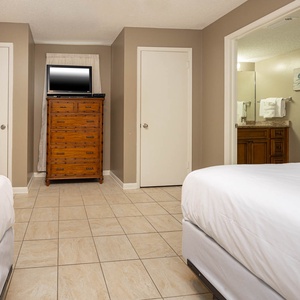 Cozy guest bedroom featuring two comfortable double beds, a wooden dresser, and a TV