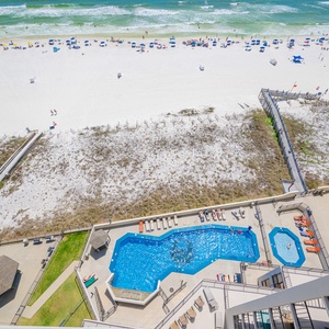 The pool's sparkling water glistens below as you listen to children's laughter mixing with distant surf on the beach