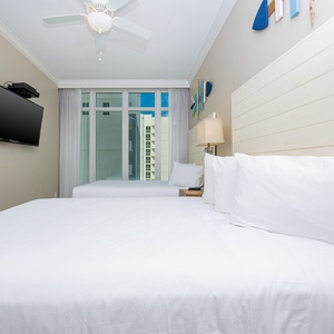 Relax in this comfortable guest bedroom featuring two queen beds, a TV, and large windows with stunning views