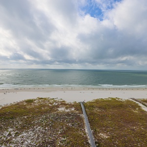 This view showcases a serene beachfront with soft sand and gentle waves, perfect for a relaxing getaway