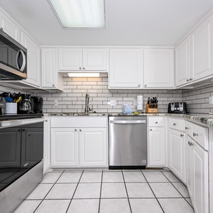 Bright white cabinetry and marbled countertops define this kitchen, featuring stainless appliances and a breakfast bar