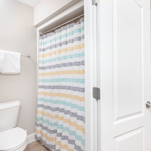 Refreshing guest bathroom featuring a colorful shower curtain, towels, and easy access to the adjacent bedroom