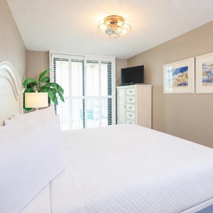 Enjoy restful nights in this master bedroom with a plush king bed, stylish decor, and natural light from the balcony