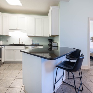White cabinetry complements the sleek black countertops in this inviting kitchen area with seating at the breakfast bar