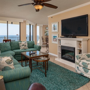 The inviting living room features a teal sectional sofa with queen sleeper, armchair, and a view of the beach