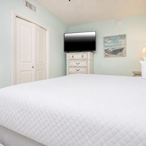 Inviting bedroom featuring a king bed, a TV for entertainment, and soft blue walls for a calming atmosphere