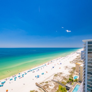 Enjoy the expansive beach view with colorful umbrellas and gentle waves, perfect for a relaxing day by the water