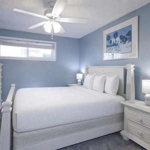 This bedroom features calming blue walls, a queen with plush pillows, and a TV for entertainment