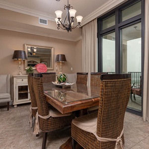 This dining area features a stylish glass-top table surrounded by woven chairs, perfect for enjoying meals with a view