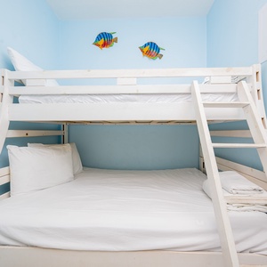 This cozy bunk room features a stylish bunk bed with white bedding and playful fish decor on soft blue walls