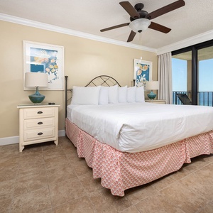 The master bedroom features a comfortable king bed, coastal decor, and sliding doors leading to a beautiful beach balcony