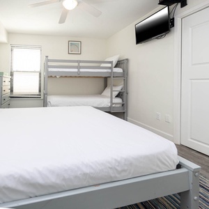 Bright and airy guest bedroom featuring a cozy queen bed and a stylish twin bunk bed, perfect for family stays