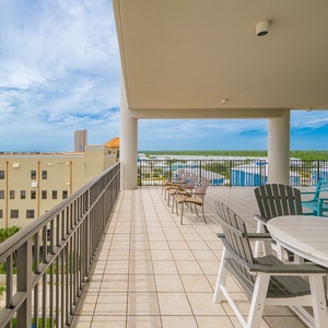 Spacious wrap-around balcony with comfortable seating offers a serene view of the beach and sparkling waters beyond