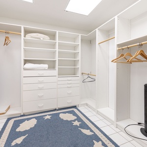 Spacious master closet, featuring ample shelving, hanging space, and a cozy area rug